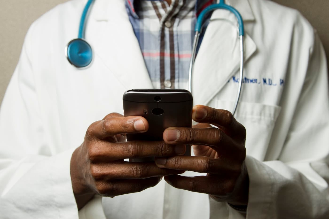 African doctor in lab coat using smartphone for digital health